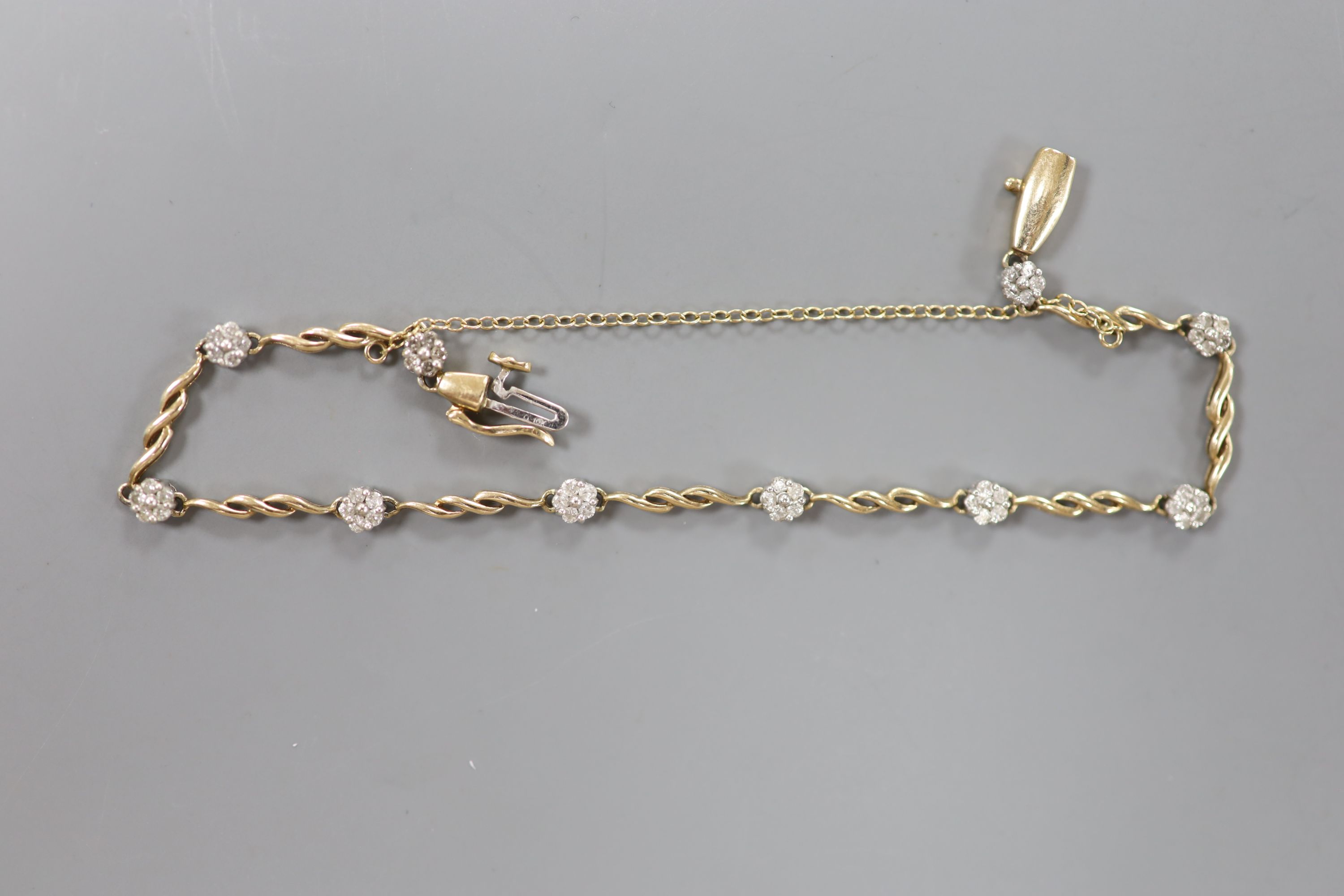 A modern 10k yellow metal and diamond chip set flower head bracelet, approx. 18cm, gross 5.3 grams.